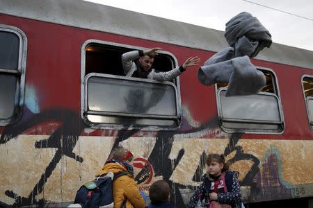 A migrant throws blankets from a train window as migrants are returned to a camp near the Macedonian-Greek border in Gevgelija, Macedonia, February 24, 2016. REUTERS/Marko Djurica