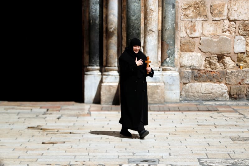 A Orthodox Christian nun holds a cross as she walks near the entrance of the Church of the Holy Sepulchre, in Jerusalem's Old City