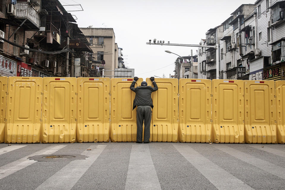 A man talks to another person through a makeshift barricade to control entry and exit to a residential compound on March 8, 2020 in Wuhan, China. (Getty Images)