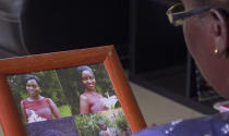 In this image taken from video, Margaret Ntale, whose three student daughters are stranded in Wuhan, looks at photographs of her children as she speaks to The Associated Press at her house in Kampala, Uganda on Thursday, Feb. 27, 2020. Parents' fears are growing for the thousands of African students who are thought to be stranded in China's locked-down city of Wuhan amid the virus outbreak, with concerns that students are running out of food and money weeks after other countries evacuated citizens. (AP Photo)