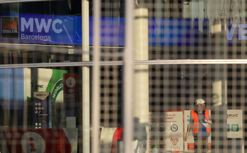 Employee is pictured next to banners with information of MWC20 (Mobile World Congress) in Barcelona