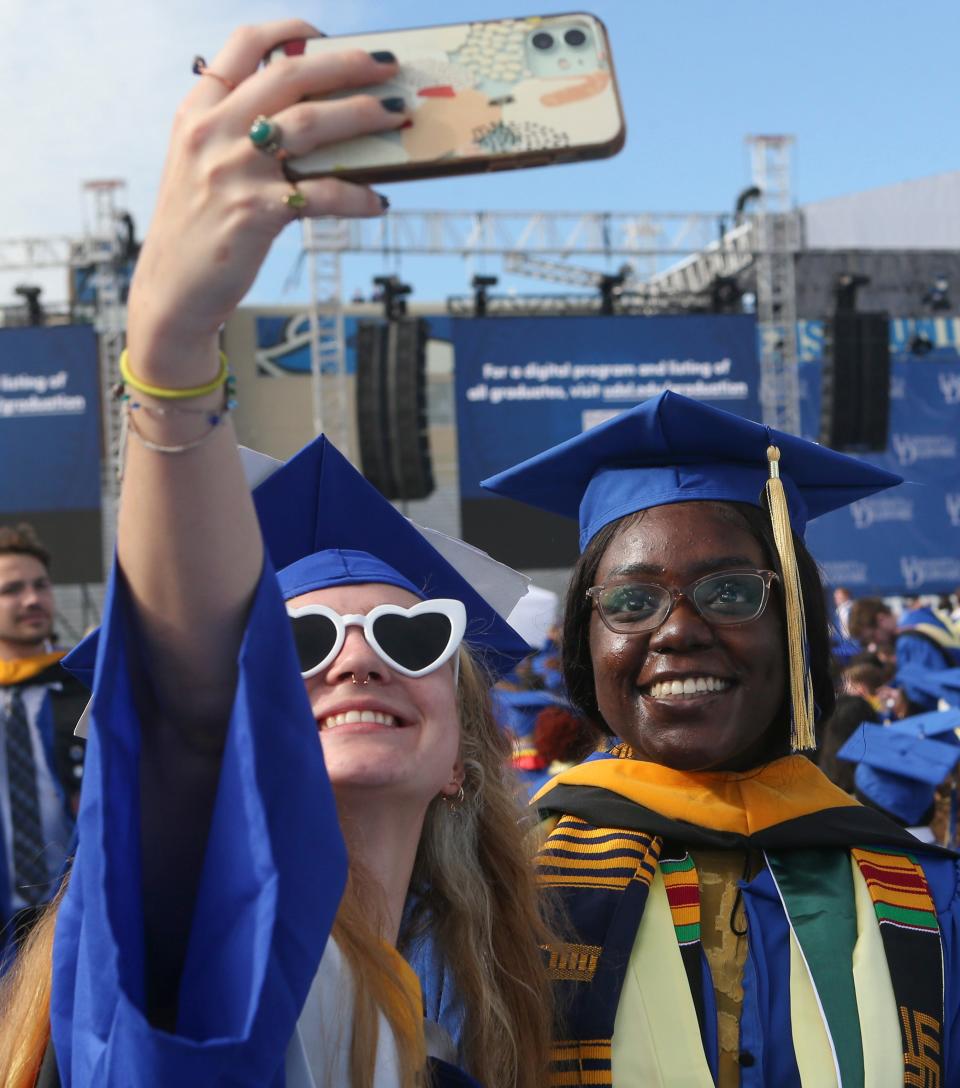 Former Newark High School classmates Cassie O'Quinn (left) of Newark (receiving a quantitative biology degreee) and Oluwaseyi Osinubi of Bear (engineering) grab a selfie before the University of Delaware's 2022 Commencement at Delaware Stadium, Saturday, May 28, 2022.