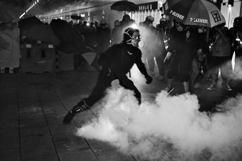 A protester throws a live tear-gas canister back at riot police during a protest near Tsim Sha Tsui police station in Kowloon, Hong Kong, on Aug. 11. | Adam Ferguson for TIME