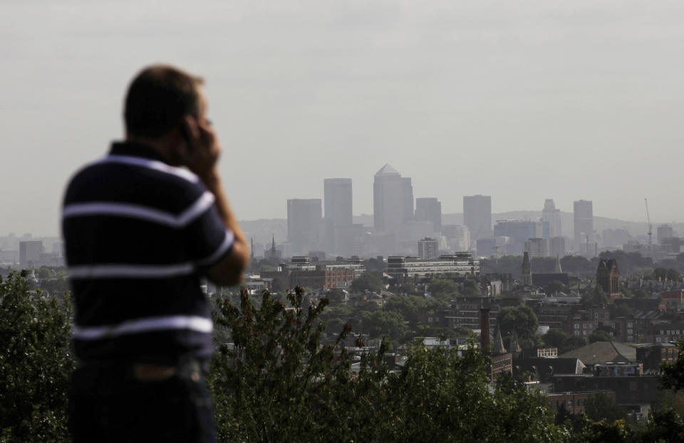 FILE In this Friday, Sept. 23, 2011 file photo a man talks on a mobile phone as the hi-rise buildings of the banks based in the Canary Wharf business district are seen in the distance from Parliament Hill on Hampstead Heath in London. British officials have given their word: 'We won't read your emails.' But experts say that its proposed new surveillance program, unveiled last week as part of the government's annual legislative program, will gather so much data that spooks won't have to read your messages to guess what you're up to. (AP Photo/Matt Dunham)
