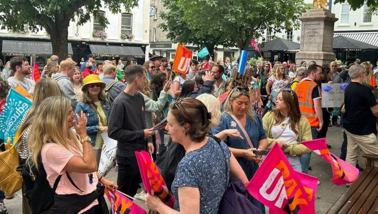 Teachers holding flags and placards at a protest