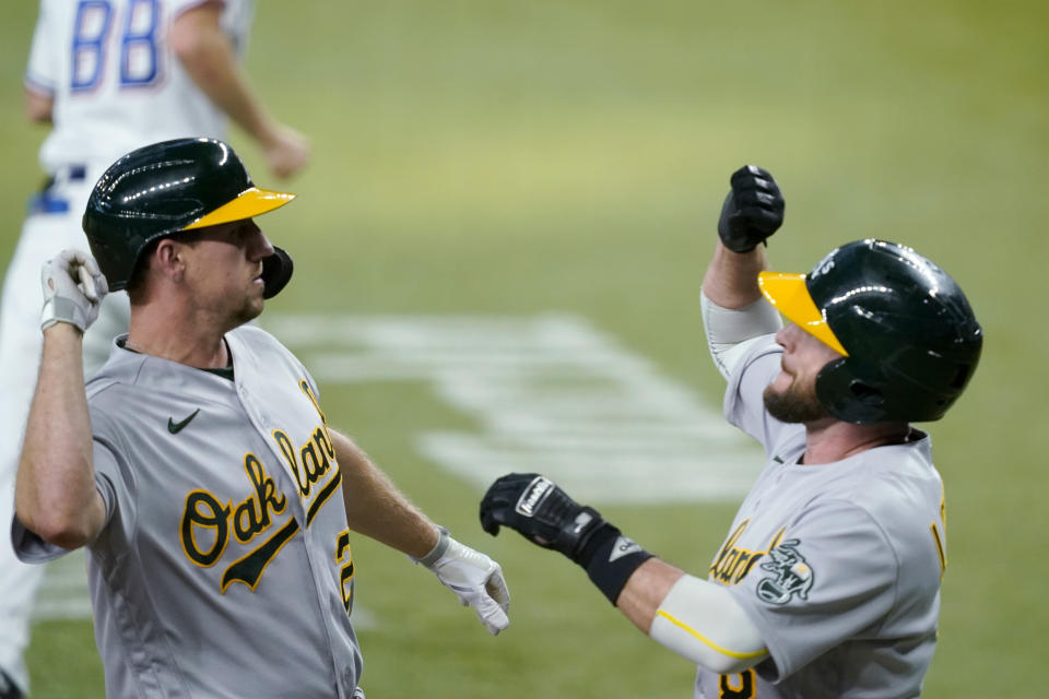 Oakland Athletics' Stephen Piscotty, left, and Jed Lowrie celebrate Piscotty's two-run home run that scored Lowrie during the 11th inning of the team's baseball game against the Texas Rangers in Arlington, Texas, Saturday, July 10, 2021. (AP Photo/Tony Gutierrez)