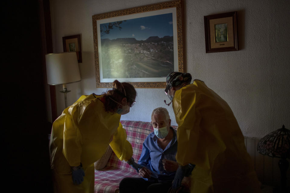 Gonzalo Garcia, 61, is examined by emergency medical workers after he suffered severe respiratory problems at his home in Barcelona, Spain, April 6, 2020. Garcia had been hospitalized with COVID-19 but was discharged after he improved, only to deteriorate in recent days. He is terrified that his second hospitalization will again leave his 91-year-old mother home alone. (AP Photo/Emilio Morenatti)