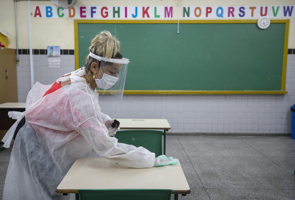 FILE - In this March 8, 2021 file photo, Marilene Paixao, the mother of a student, disinfects a desk in a classroom of the EMEF Sylvia Martin Pires public school in Sao Paulo, Brazil. When Sao Paulo city officials put out a call last month for 4,500 public school cleaning jobs, targeting Brazilian mothers affected by the raging pandemic, they were unprepared for the ensuing tsunami. More than 90,000 women applied in just two days. (AP Photo/Andre Penner, File)