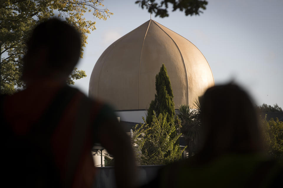 Mourners stand in front of the Masjid Al Noor mosque in Christchurch, New Zealand, Tuesday, March 19, 2019. Christchurch was beginning to return to a semblance of normalcy Tuesday. Streets near the hospital that had been closed for four days reopened to traffic as relatives and friends of Friday's shooting victims continued to stream in from around the world. (AP Photo/Vincent Thian)