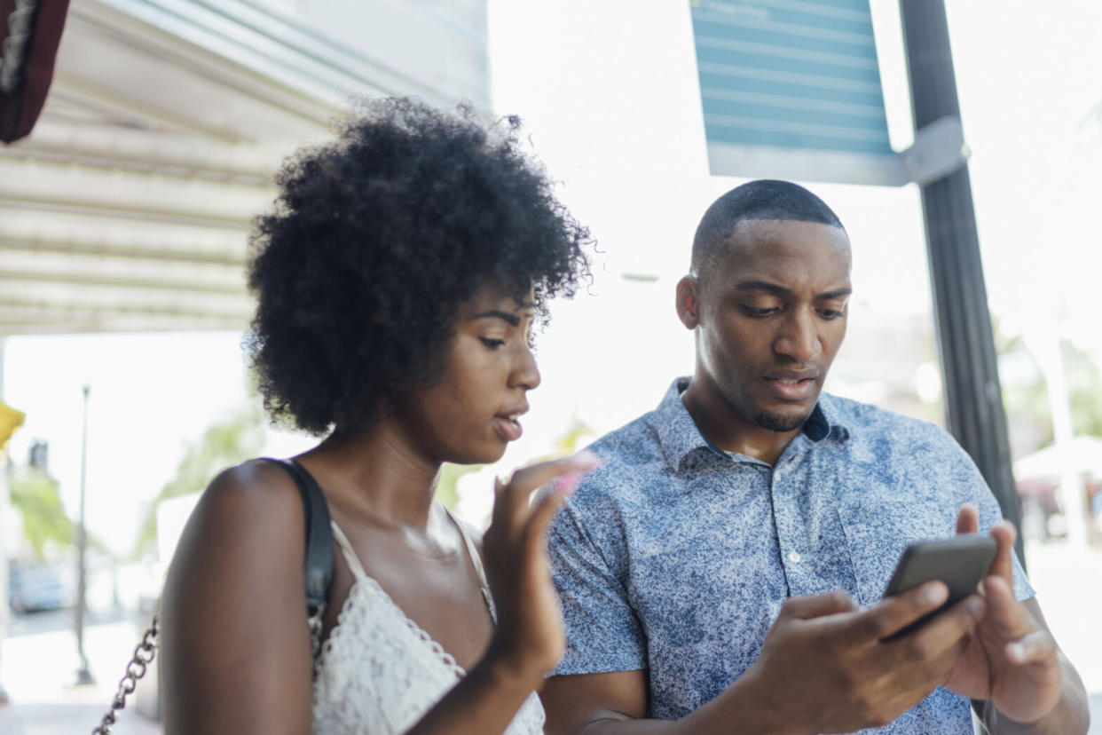 young couple using cell phone in the city