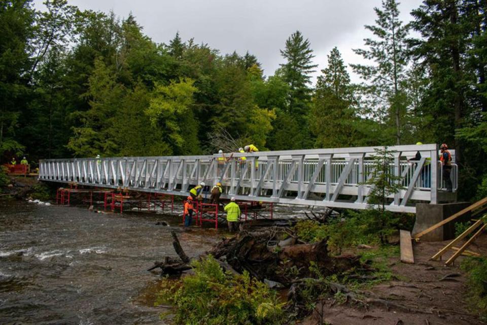 Workers assemble sections of the Lower Falls accessibility bridge at Tahquamenon Falls State Park.