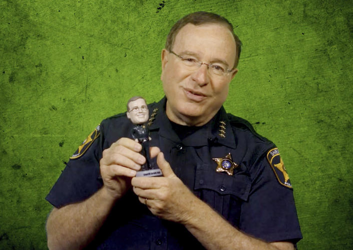 In this undated image taken from video and made available by the Polk County, Fla., Sheriff's Office, Sheriff Grady Judd holds a bobblehead of his likeness given to him by his staff. The bobble head and others like it were sold to benefit the Sheriff department charities. Sheriff Judd, with his folksy Southern drawl, uses social media to target drug dealers, prostitution rings, gangs and human traffickers. (Polk County Sheriff's Office via AP)