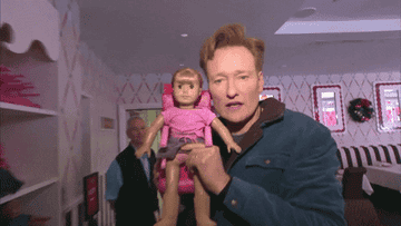 Conan O'Brien holds a doll next to his face