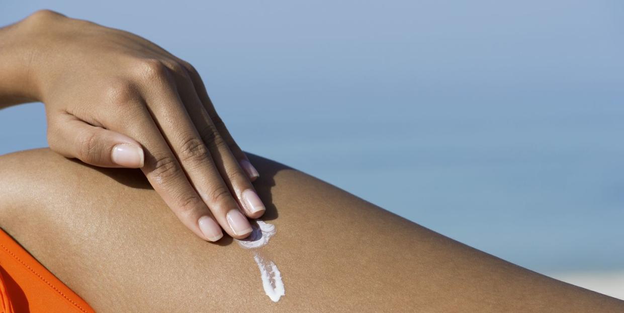 woman applying suncreen at the beach, cropped