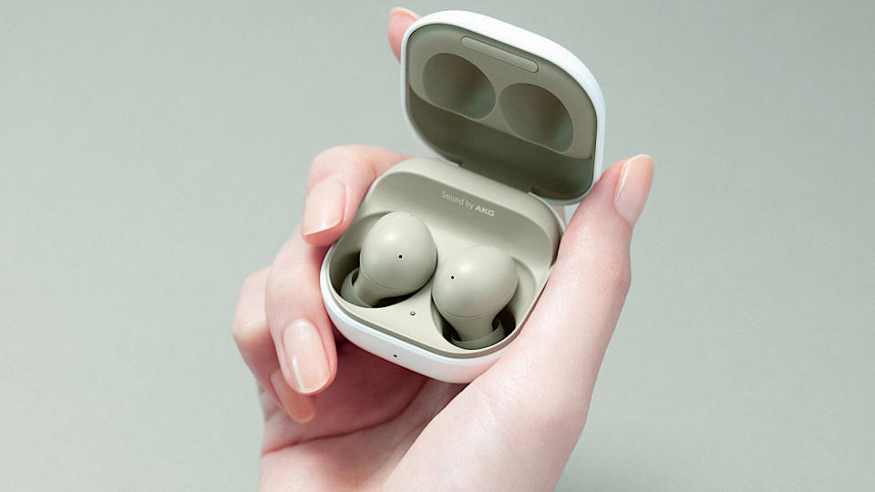 A hand holding the samsung galaxy buds 2 in olive