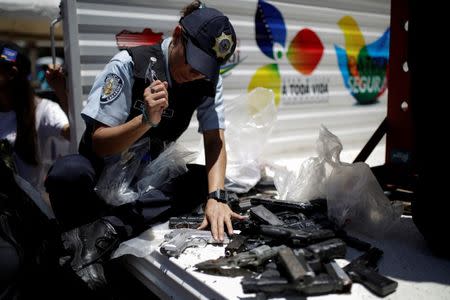 A police officer hammers a pistol during an exercise to destroy seized weapons in Caracas, Venezuela August 17, 2016. REUTERS/Marco Bello