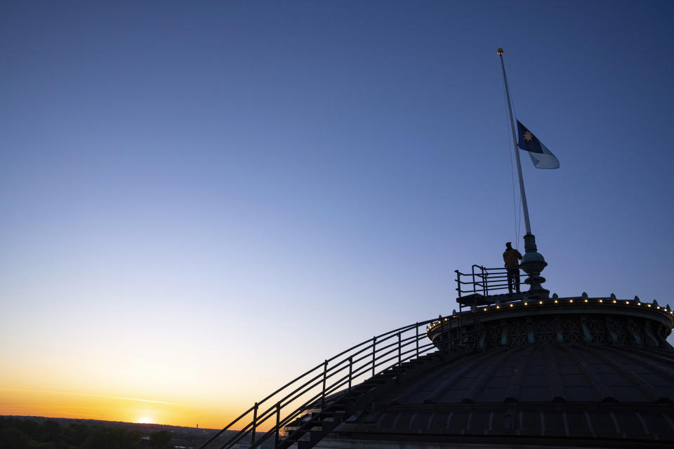 Charlie Krueger, a grounds supervisor for facilities management at the Department of Administration, raises the new Minnesota state flag for the first time at sunrise atop the Minnesota State Capitol in St. Paul, Minn., on Saturday, May 11, 2024. Minnesota officially unfurled its new state flag atop the capitol for the first time Saturday on statehood day. (Alex Kormann/Star Tribune via AP)