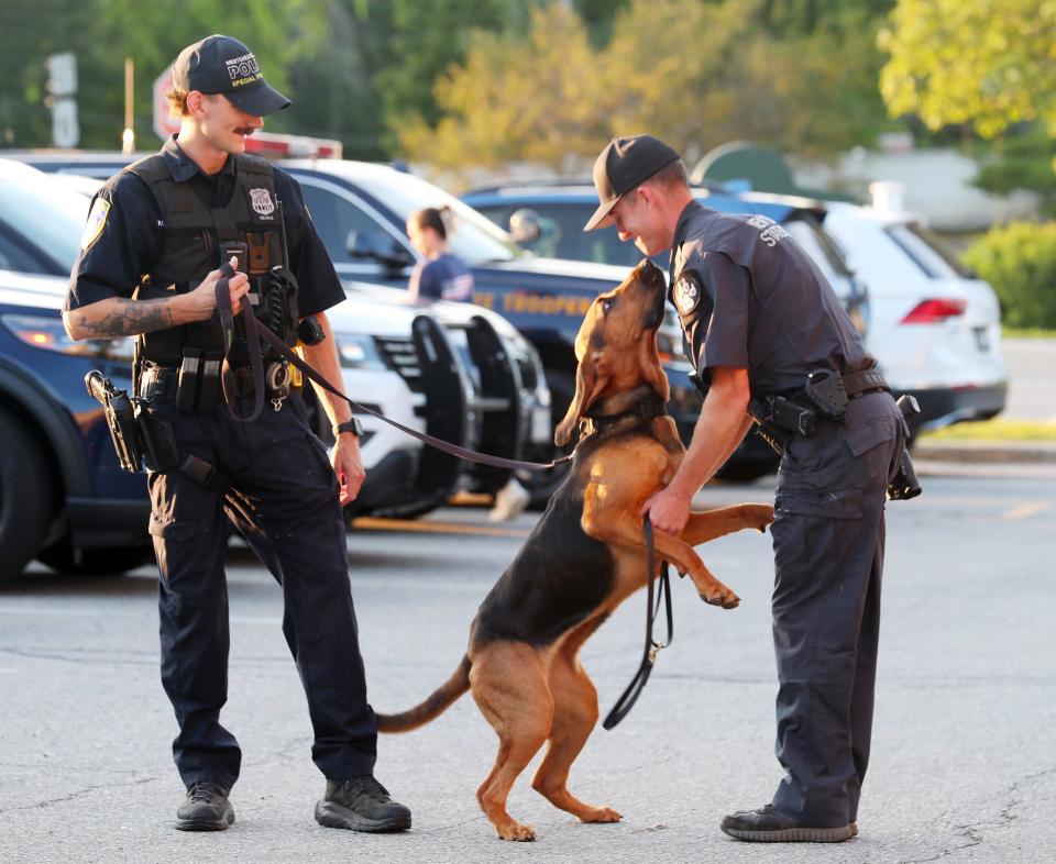 From left, Westchester County Police Officer Chris Hearle watches as his K-9 partner Wren greets New York State Trooper Patrick Porteus outside Carmel Town Hall Aug. 2, 2023. A ceremony was held at town hall honoring first responders who assisted in a 5-day search for an elderly missing Mahopac man who was found alive on Monday.