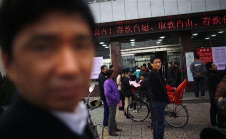 People gather in front of a branch of Rural Commercial Bank of Huanghai in Yancheng, Jiangsu province, March 26, 2014. REUTERS/Carlos Barria