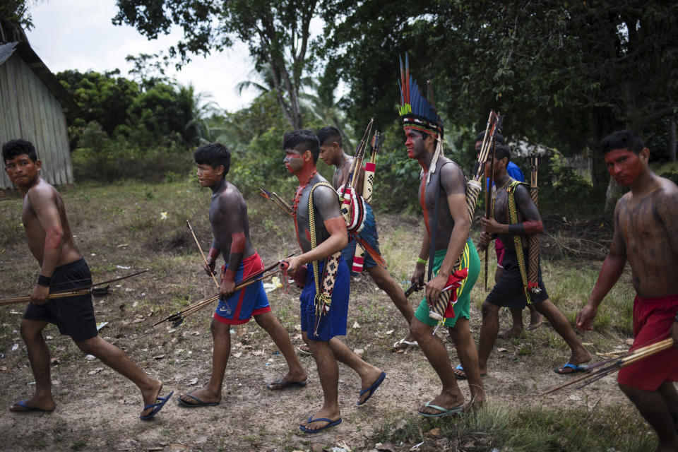 In this Sept. 3, 2019 photo, villagers arrive to a meeting of Tembé tribes in Tekohaw indigenous reserve, Para state, Brazil. Some of the men wear a type of red face paint that signifies they are ready for war. Recent clashes saw the Tembe burning the trucks and equipment of illegal loggers on their territory, which is located in a Brazilian state plagued by thousands of fires burning on cleared jungle lands. (AP Photo/Rodrigo Abd)