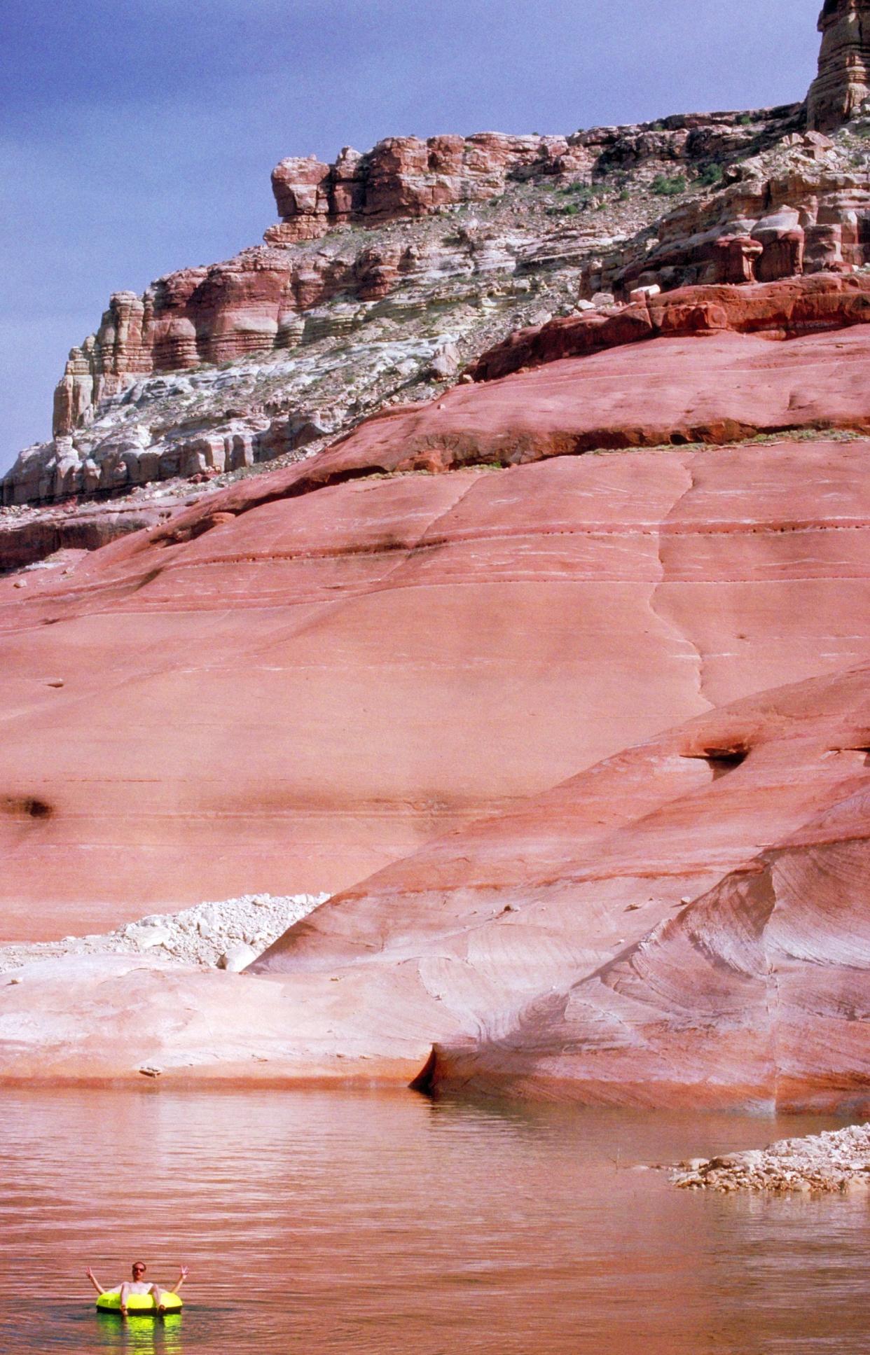 Man floating in an colorful tube on Lake Powell in Utah/Arizona.