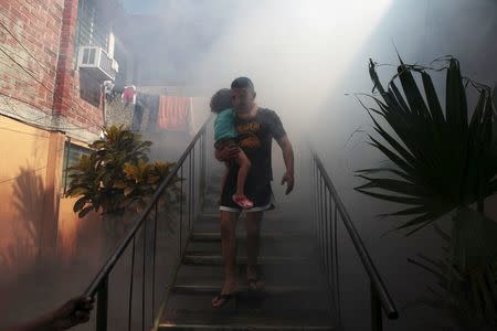 A man walks away from his home with his son as health workers fumigates the Altos del Cerro neighbourhood as part of preventive measures against the Zika virus and other mosquito-borne diseases in Soyapango, El Salvador January 21, 2016. REUTERS/Jose Cabezas