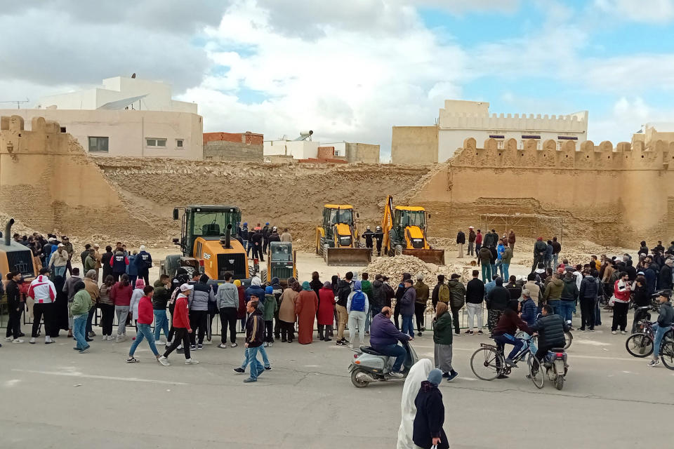 People and Civil Protection members gather at the site of a collapsed section of the ancient wall surrounding historic Kairouan in central Tunisia, killing three workers, on December 16, 2023.