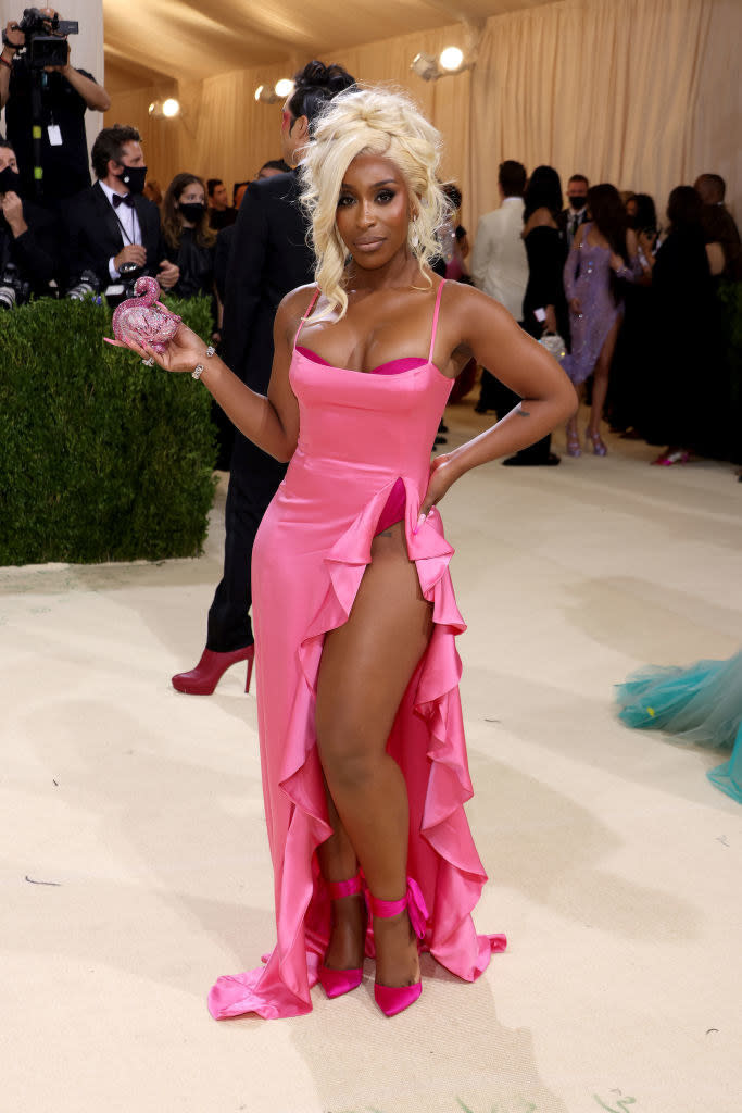 Jackie Aina wears a brightly colored thin strap gown with a high slit up her thigh