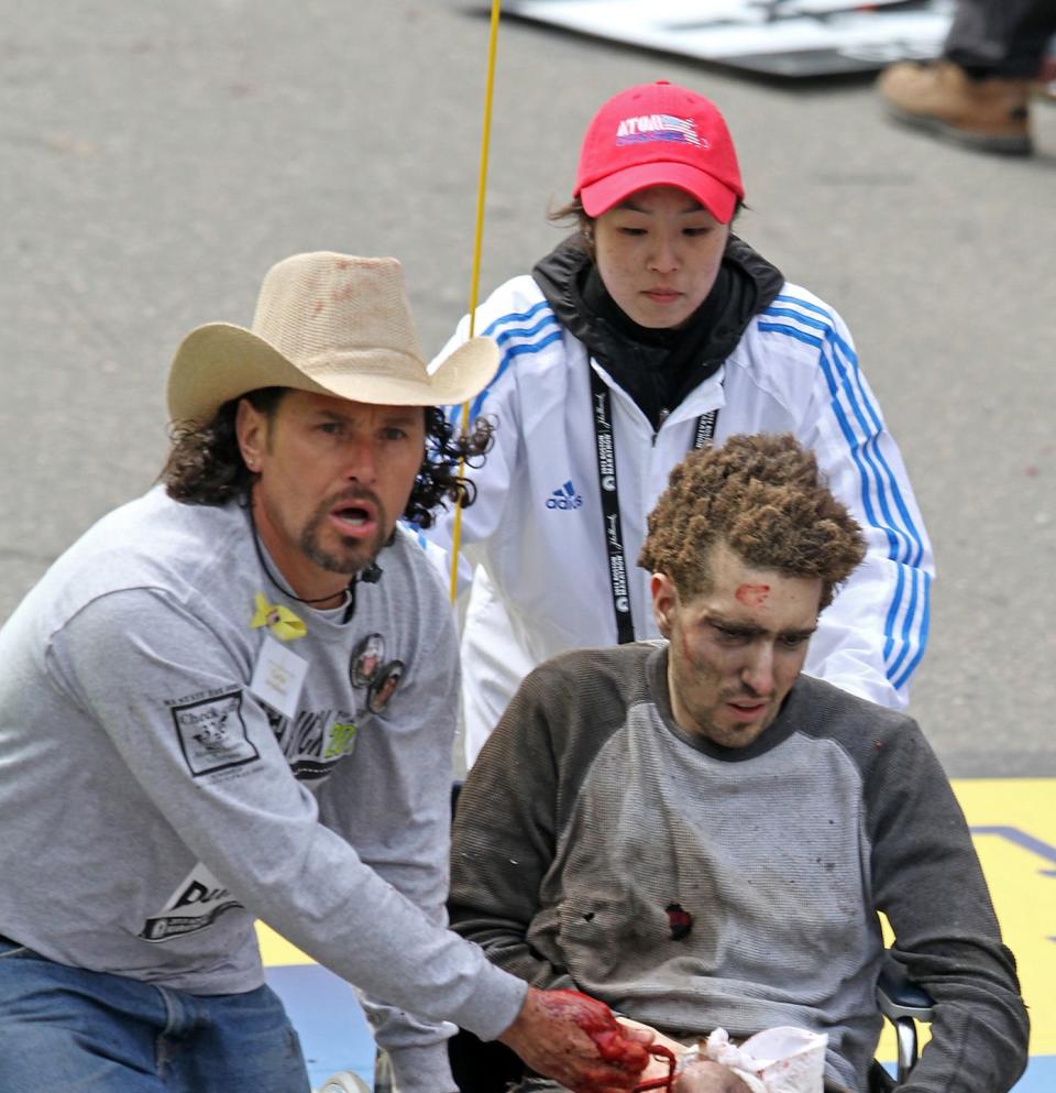 carlos arrondondo, wearing a cowboy hat, helping helping the injured jeff bauman in a wheelchair