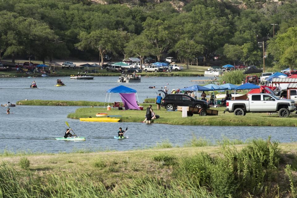 People celebrating the Fourth of July gather along the shore of Buffalo Springs Lake to play in the water and cook before the fireworks display on Friday, July 3, 2020, in Buffalo Springs, Texas.