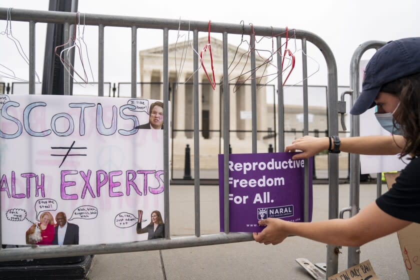 WASHINGTON, DC - MAY 14: Abortion rights activists put signs and hangers back onto barriers after they were removed by Capitol Police officers during a Bans Off Our Bodies rally and march to the Supreme Court of the United States on Supreme Court of the United States on Saturday, May 14, 2022 in Washington, DC. Abortion rights supporters are holding rallies across the country urging lawmakers to codify abortion rights into law after a leaked draft from the Supreme Court revealed a potential decision to overturn the precedent set by landmark Roe v. Wade. (Kent Nishimura / Los Angeles Times)