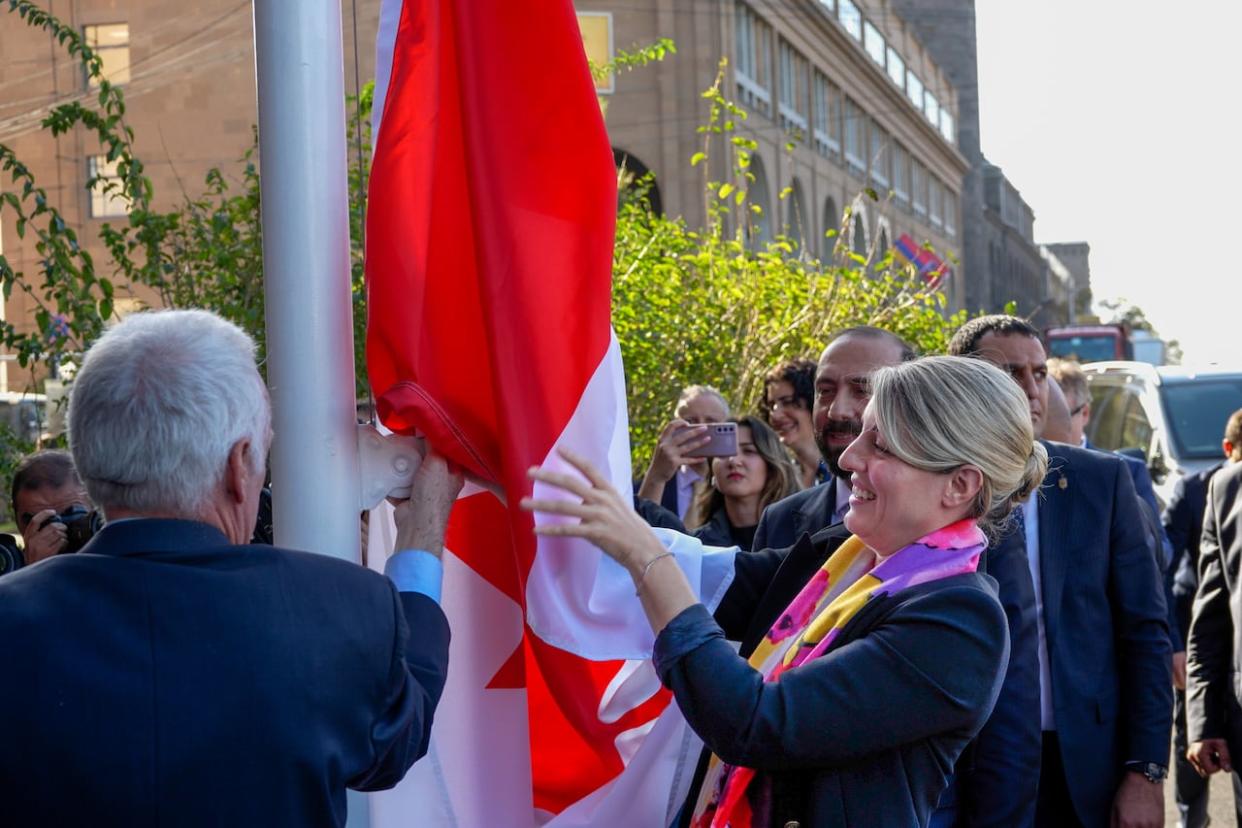 Foreign Affairs Minister Mélanie Joly helps inaugurate the Canadian embassy in Yerevan, Armenia by raising the flag during an official visit, as her Armenian counterpart Ararat Mirzoyan and others look on.  (Fin DePencier/CBC  - image credit)