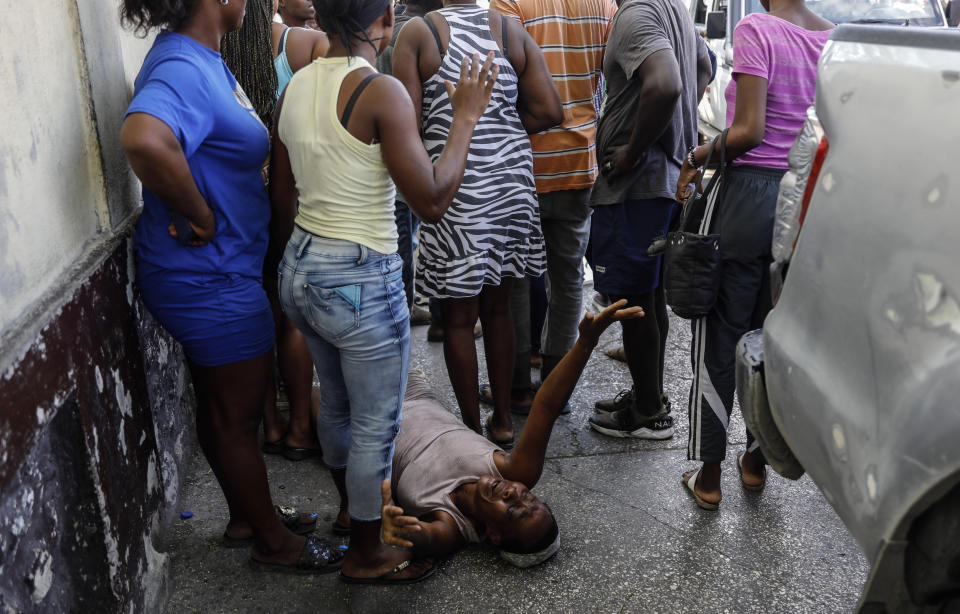 A woman lies on the pavement as she mourns a family member shot dead by unknown assailants as he sat on his motorcycle in the Delmas area of Port-au-Prince, Haiti, Friday, March 8, 2024. (AP Photo/Odelyn Joseph)