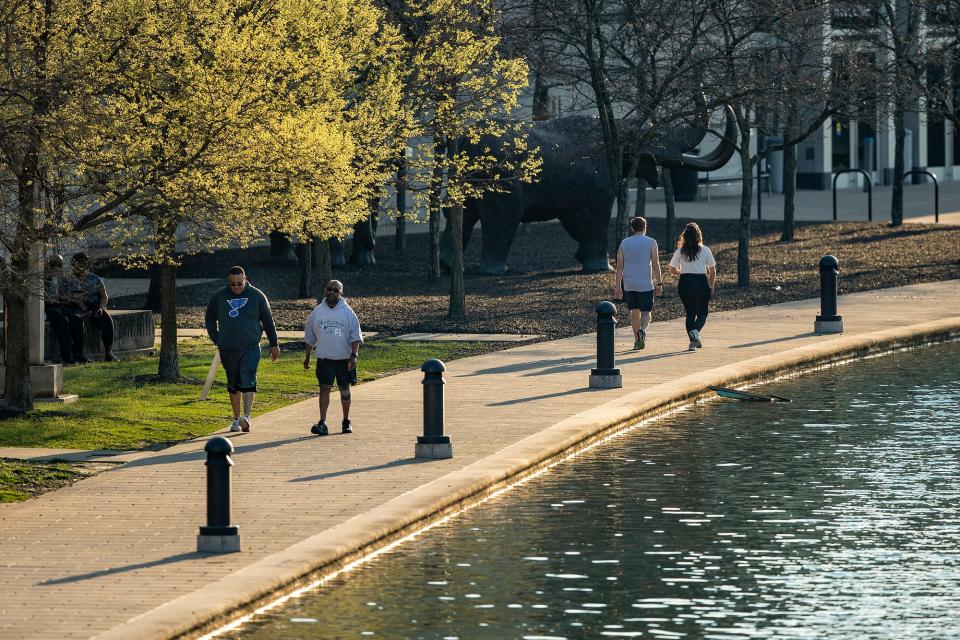 Pedestrians walk and run along the Canal Walk near the West Street underpass in Indianapolis on Tuesday evening, April 7, 2020. Spring warmth arrived in Indy this week, with temperatures hitting the high-70s at their peak on Tuesday and Wednesday. 