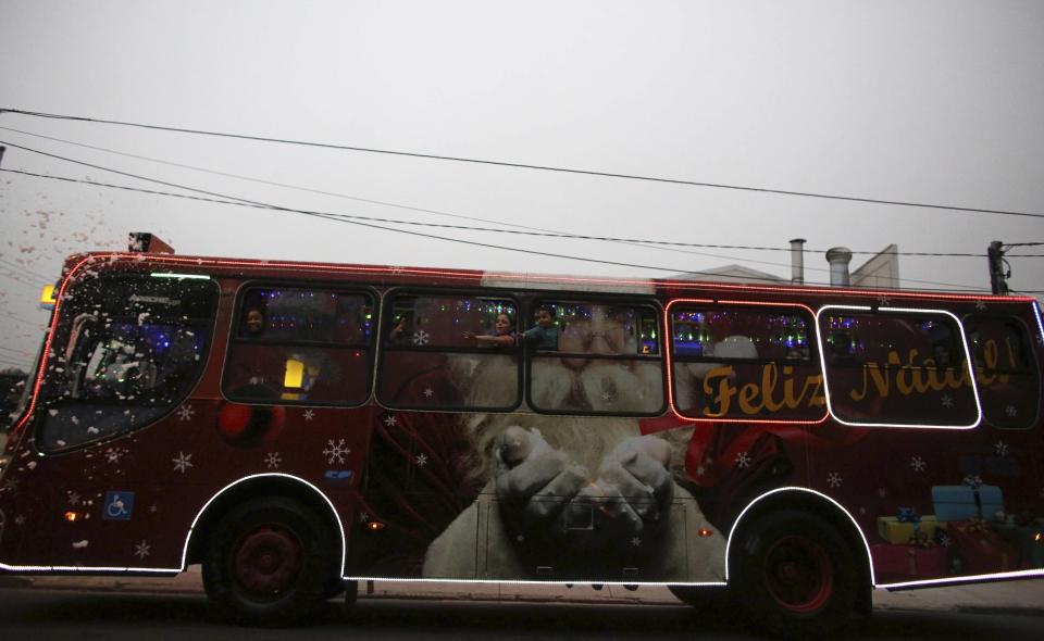 Bus driver Edilson, 45, also known as "Fumassa", drives while wearing a Santa Claus outfit inside an urban bus decorated with Christmas motives in Santo Andre, outskirts of Sao Paulo December 10, 2013. Fumassa dresses as Santa Claus every year while driving his bus. Picture taken December 10. REUTERS/Nacho Doce (BRAZIL - Tags: SOCIETY TRANSPORT)