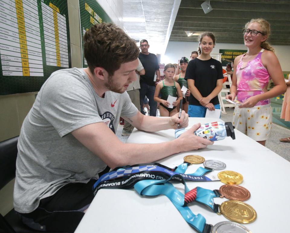 Olympic gold medalist Hunter Armstrong signs a water bottle for 12-year-old Khloe Finefrock at the Massilon YMCA. The Dover native stopped at the Y to talk to the members of the Gator swim team.