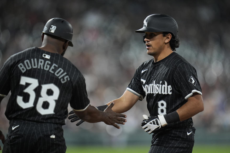 Chicago White Sox's Nicky Lopez, right, slaps hands with first base coach Jason Bourgeois, left, after hitting a single that allowed Dominic Fletcher to score during the fourth inning of a baseball game against the New York Yankees, Monday, Aug. 12, 2024, in Chicago. (AP Photo/Erin Hooley)