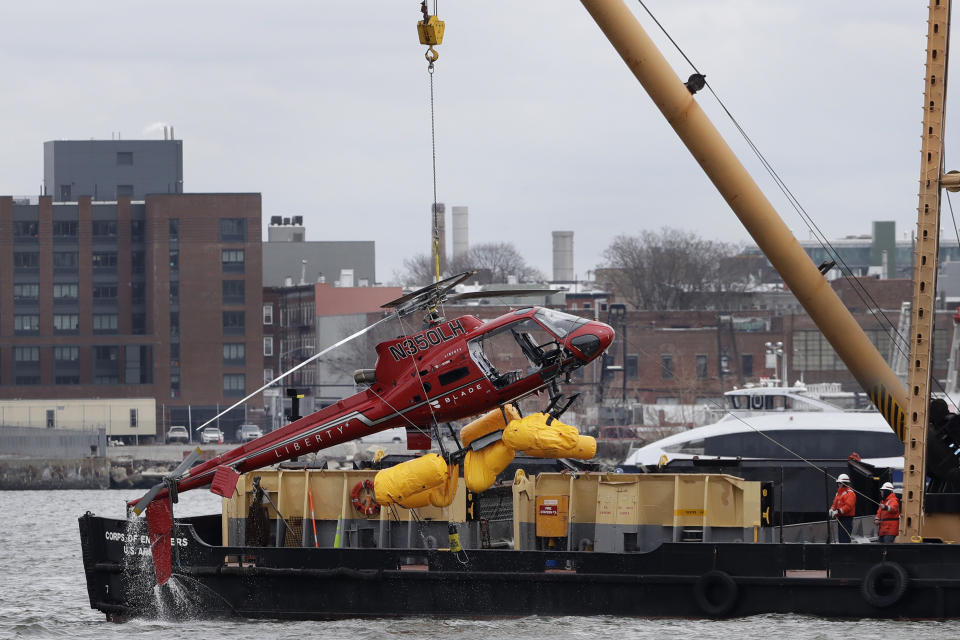 FILE - A helicopter is hoisted by crane from the East River onto a barge in New York on Monday, March 12, 2018. (AP Photo/Mark Lennihan, File)