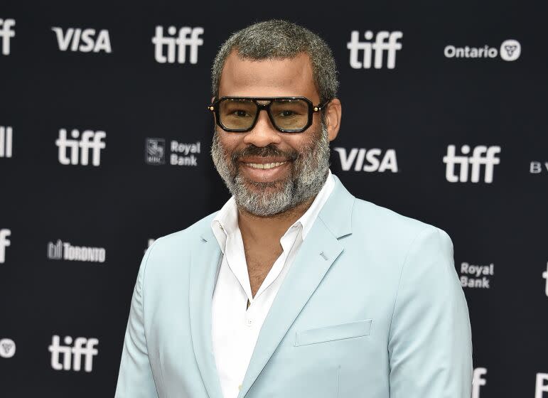 Jordan Peele wearing dark sunglasses and a light blue suit