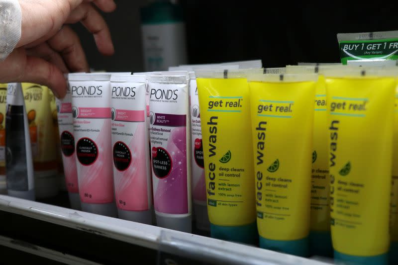 A worker arranges Pond's face wash from Hindustan Unilever next to Reliance's Get Real face wash on a shelf inside a Reliance supermarket in Mumbai