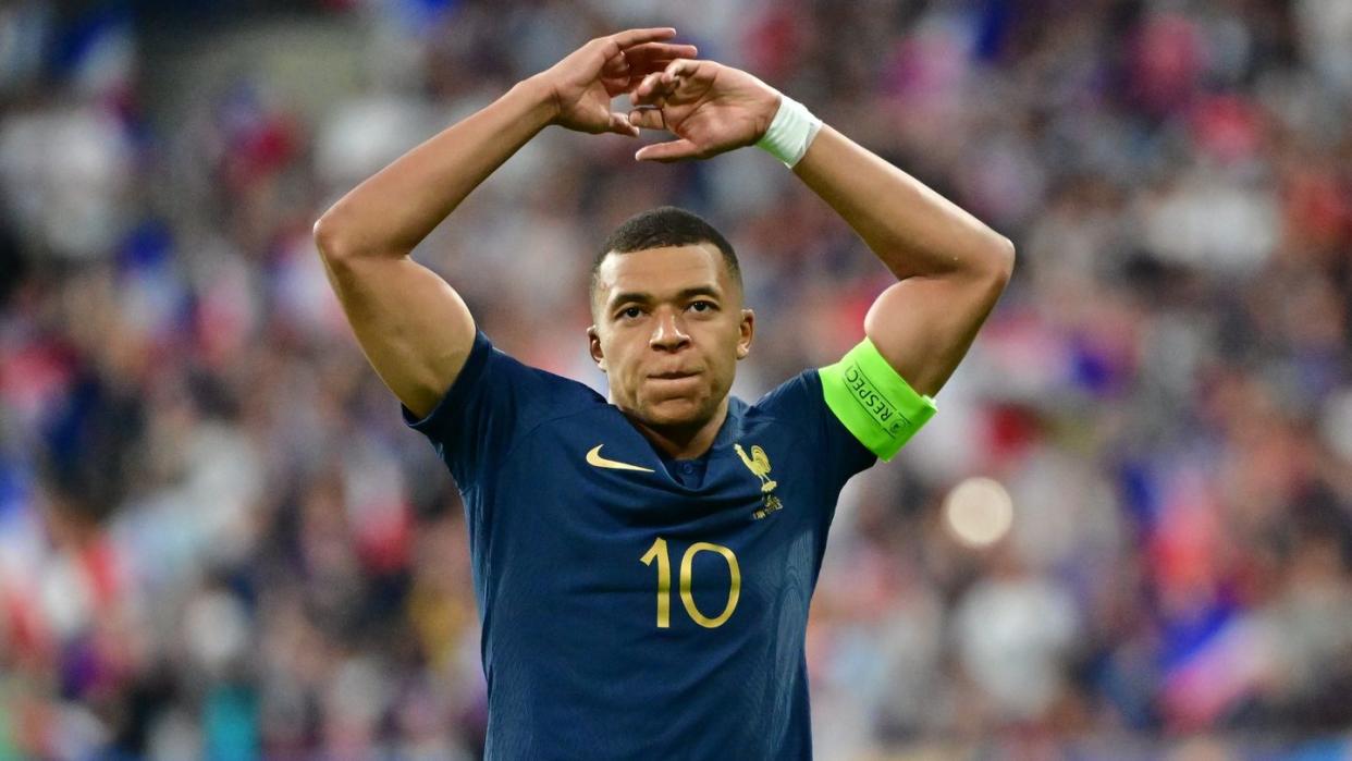 kylian mbappe gesturing with bth of his arms raised over his head
