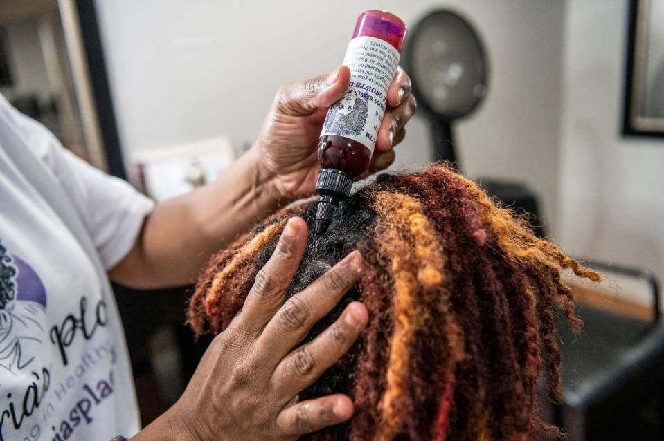 Sherria Heath applies her product, Mauri's Miracle Growth Oil, onto the scalp of her daughter Sha'Mauri Chase-Heath on Monday, Nov. 15, 2021, inside her home salon in Battle Creek, Michigan.