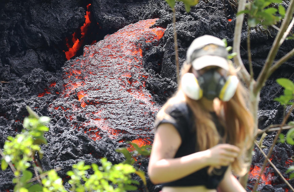 Lava flows at a new fissure in the aftermath of eruptions from the Kilauea volcano on Hawaii's Big Island as a local resident walks nearby after taking photos on May 12, 2018.