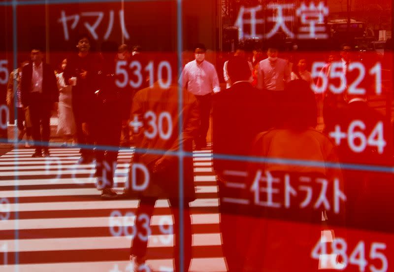 FILE PHOTO: Passersby are reflected on an electric stock quotation board outside a brokerage in Tokyo