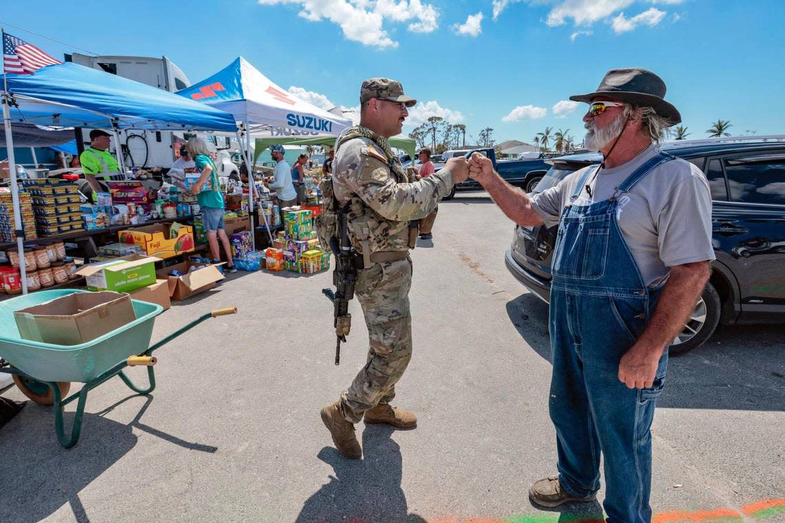 Florida Army National Guard Sgt. Steven May fist bumps Douglas Martin, 66, at a Hurricane Ian relief supply station in St. James City, an unincorporated community, on Pine Island on Tuesday, Oct. 4, 2022.