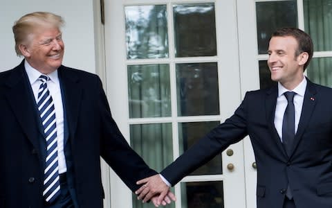 Donald Trump and Emmanuel Macron hold hands outside of the White House - Credit: AFP PHOTO / Brendan Smialowski