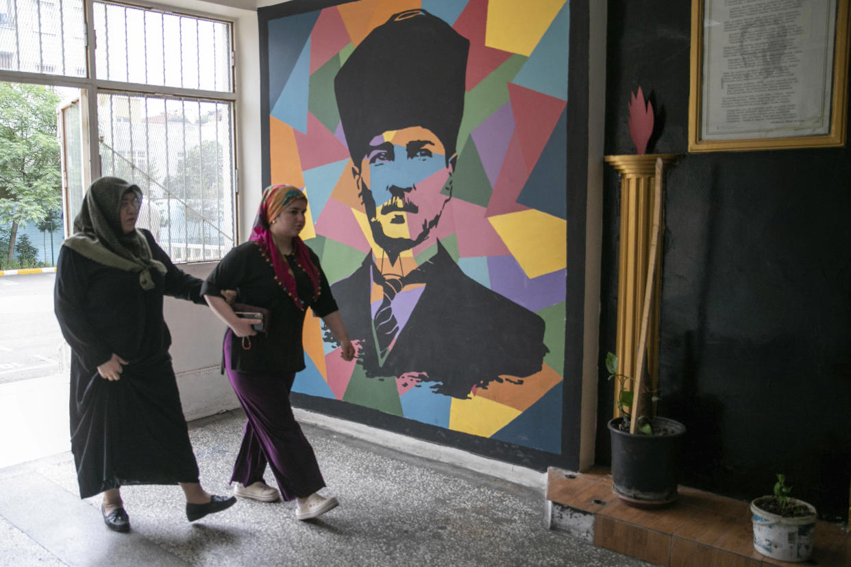 Two women walk past an image of Mustafa Kemal Ataturk, the founder of modern Turkey, as they arrives to vote at a polling station at a primary school, in Diyarbakir, Turkey, Sunday, May 28, 2023. Voters in Turkey returned to the polls Sunday to decide whether the country’s longtime leader, President Recep Tayyip Erdogan, stretches his increasingly authoritarian rule into a third decade or is unseated by a challenger who has promised to restore a more democratic society. (AP Photo/Metin Yoksu)