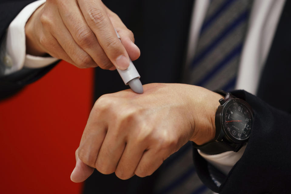 Yoshiyuki Matsuo, assistant brand manager of uno Group of Shiseido Japan Co., Ltd, a Japanese multinational cosmetic and personal care brand, shows the brand's latest lip balm for men, colored in grey, but the color turns red when it touches skins, in Tokyo Thursday, April 15, 2021. A large personal care company, Shiseido, says one of its male makeup lines has seen double-digit growth during the coronavirus pandemic. Company officials give a similar reason: Men, confronted with the sight of their faces repeatedly during online meetings, want to improve what they see. (AP Photo/Eugene Hoshiko)