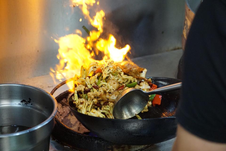 Owner Jeff Kong pushing the food toward the back of the wok, allowing the flame to give the dish a bit of smoky flavor. Mr. K Authentic Chinese, 5048 Yadkin Road, Fayetteville.