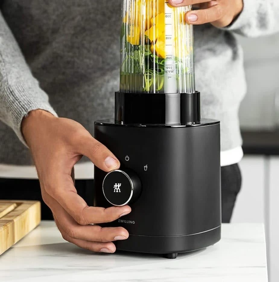 Person using a Zwilling electric pasta maker to extrude fresh spaghetti